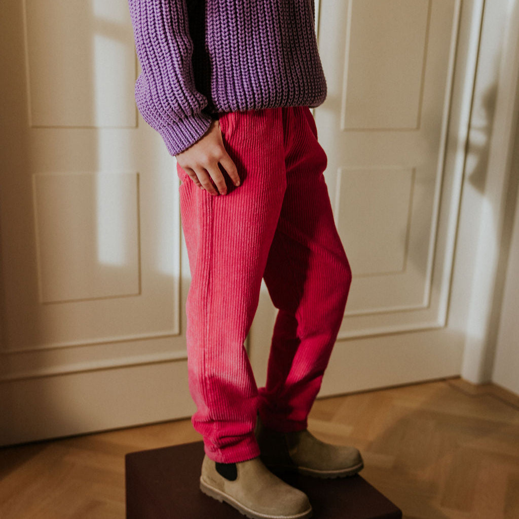 Fuchsia corduroy broek aan bij een kind met een wit strikje van het merk Yuki