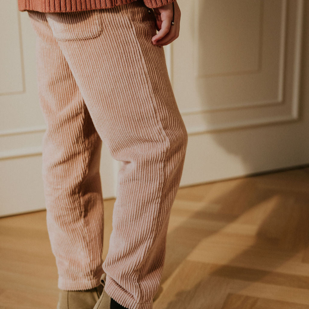 Vintage pink corduroy broek met een wit strikje achterkant aan bij een kindje van het merk Yuki