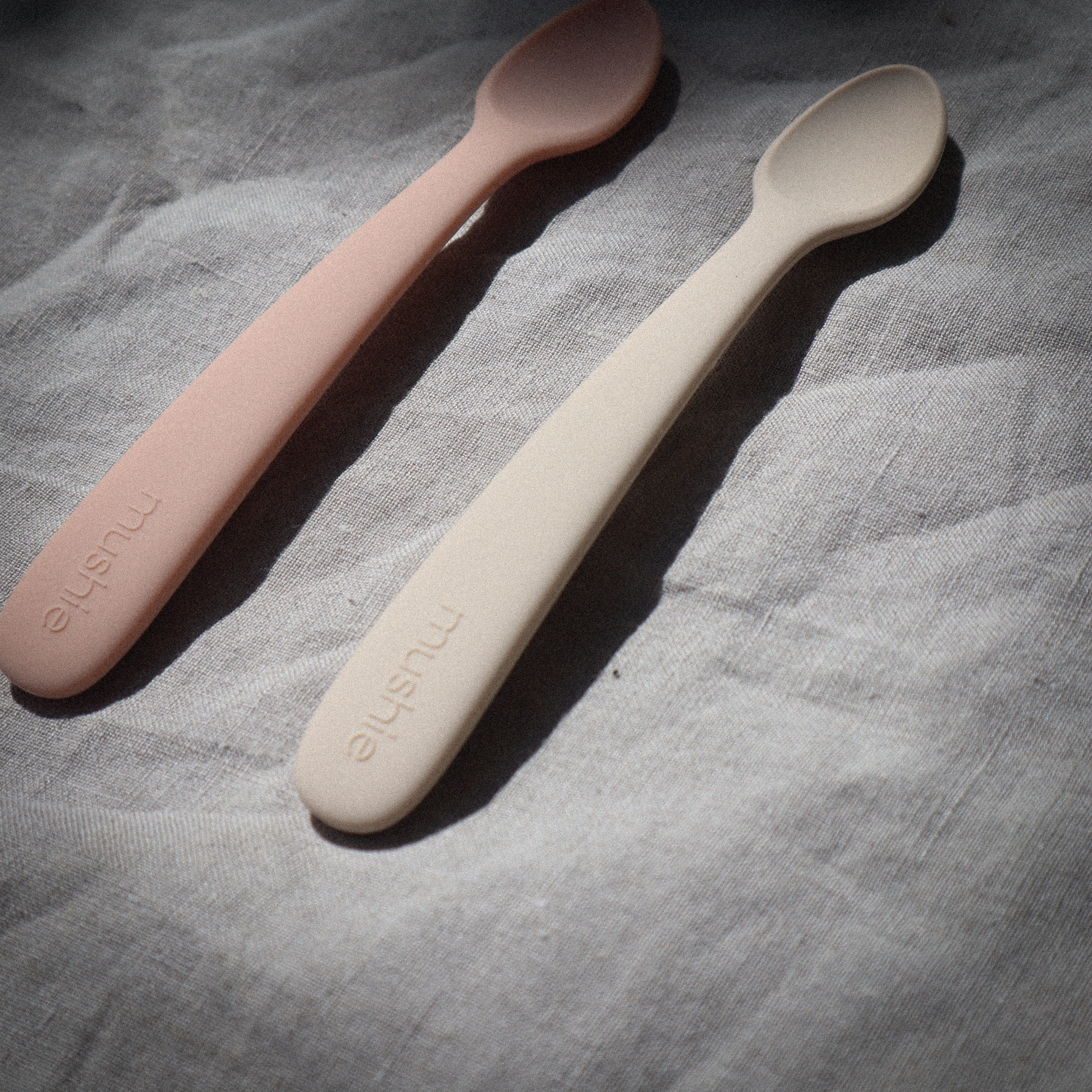 Twee lepels van baby's (kinderen) in het naturel en rose om te eten van Mushie.