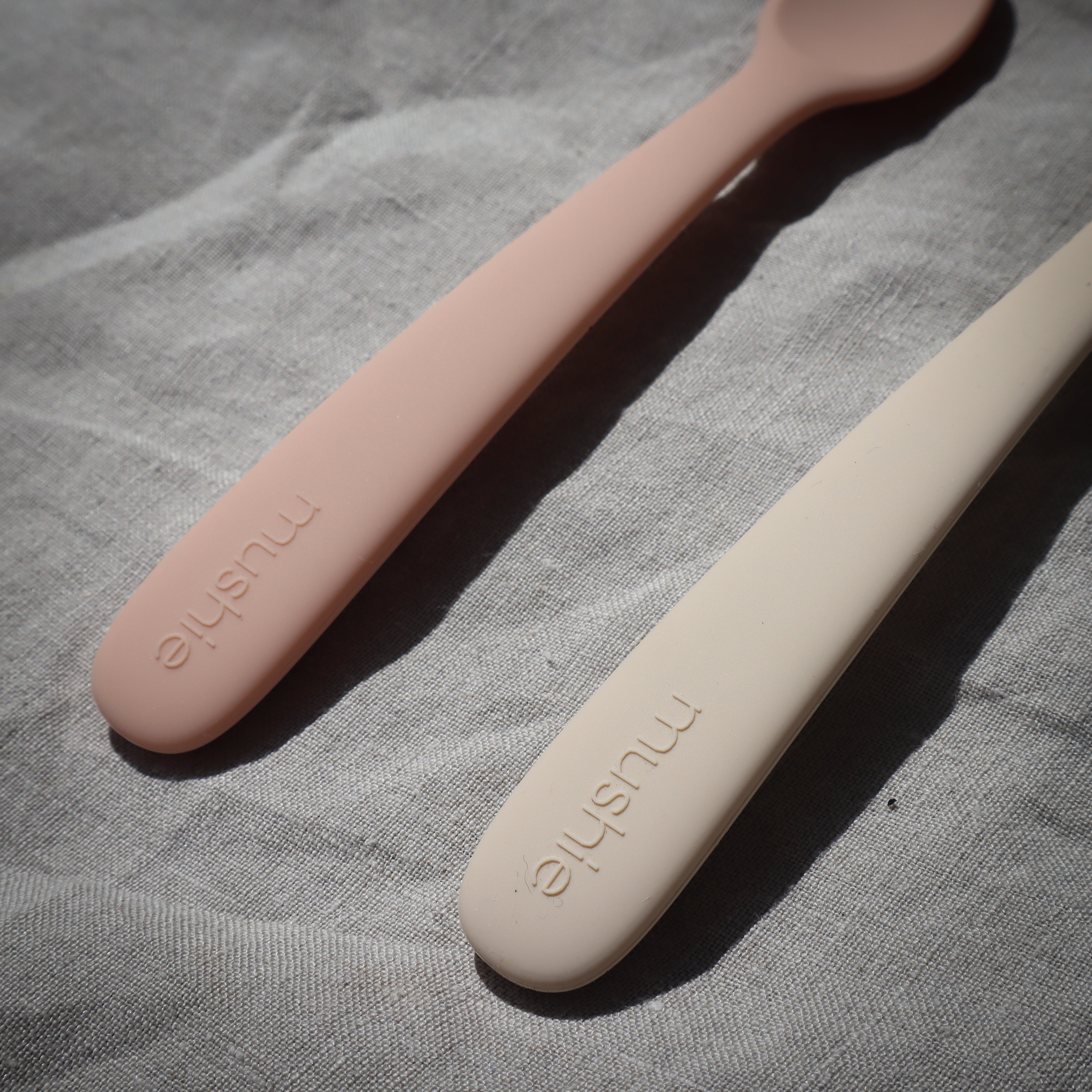 Twee lepels van baby's (kinderen) in het naturel en rose om te eten van Mushie.