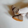 Babyslofjes wool Enfant in de kleur bruin met klittenband sluiting voor baby's met rustige achtergrond.