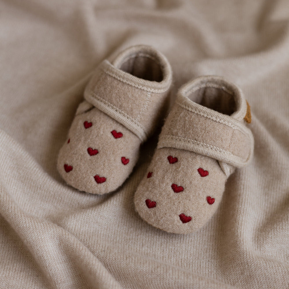 Babyslofjes in beige kleur met hartjes liggens op een kleed met klittenband van het merk ENFANT 