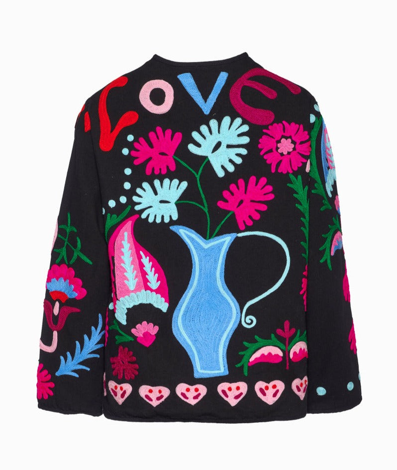 Maggie Suzani Love Jacket mt 'Love' op de achterkant bestaat uit een katoenen canvas met opvallende Suzani borduurwerk. Het jasje heeft zakken aan de voorkant en knopen middenvoor. Je ziet de Indiaanse inspiratie aanwezig in de borduur ontwerpen waarbij traditionele Indiase motieven zijn gemengd met universele en eigentijdse symbolen als harten, liefde en klaproosbloemen. 