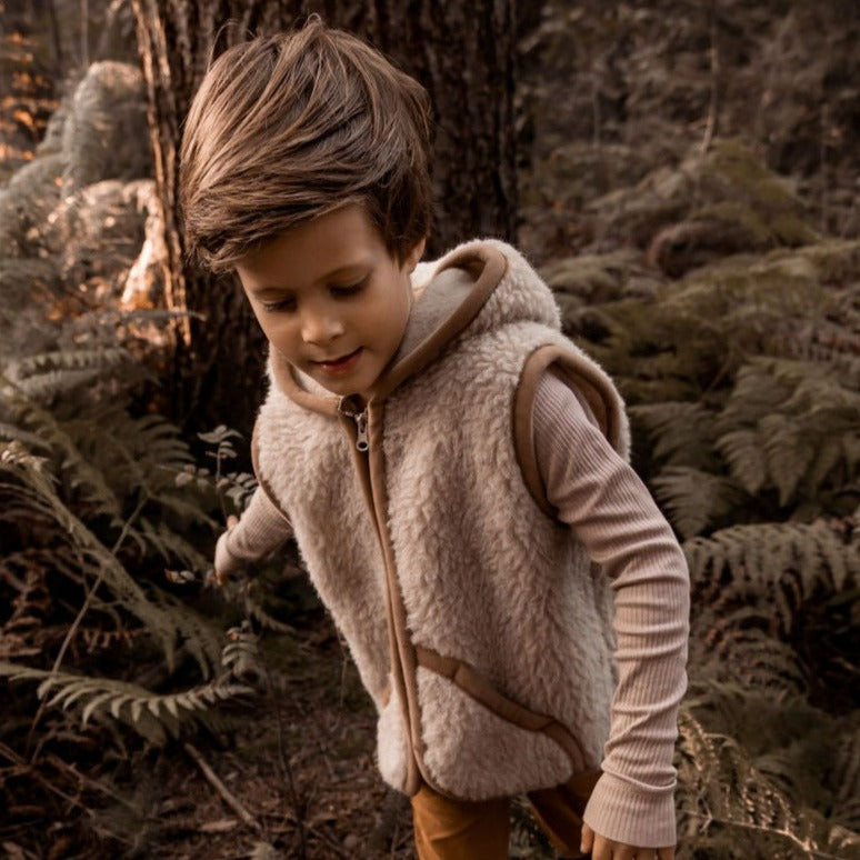 Kind draagt beige wollen bodywarmer met capuchon van het merk Alwero 