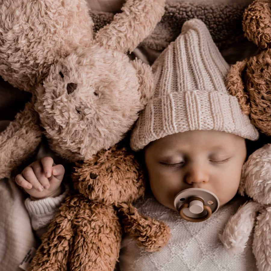 De slaapknuffel van Moonie in de vorm van een beer in de kleur cappuccino voor baby's die rustgevende geluiden maakt die de slaap bevorderen voorzijde. 
