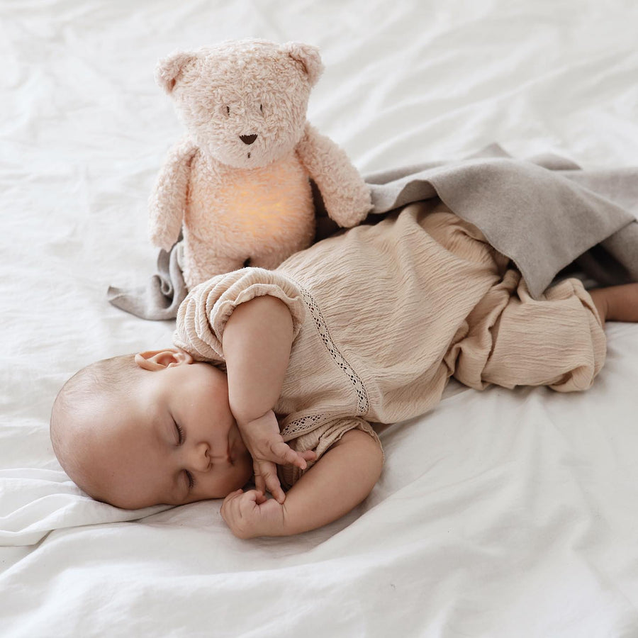 De slaapknuffel van Moonie in de vorm van een beer in de kleur rose voor baby's die rustgevende geluiden maakt die de slaap bevorderen. 